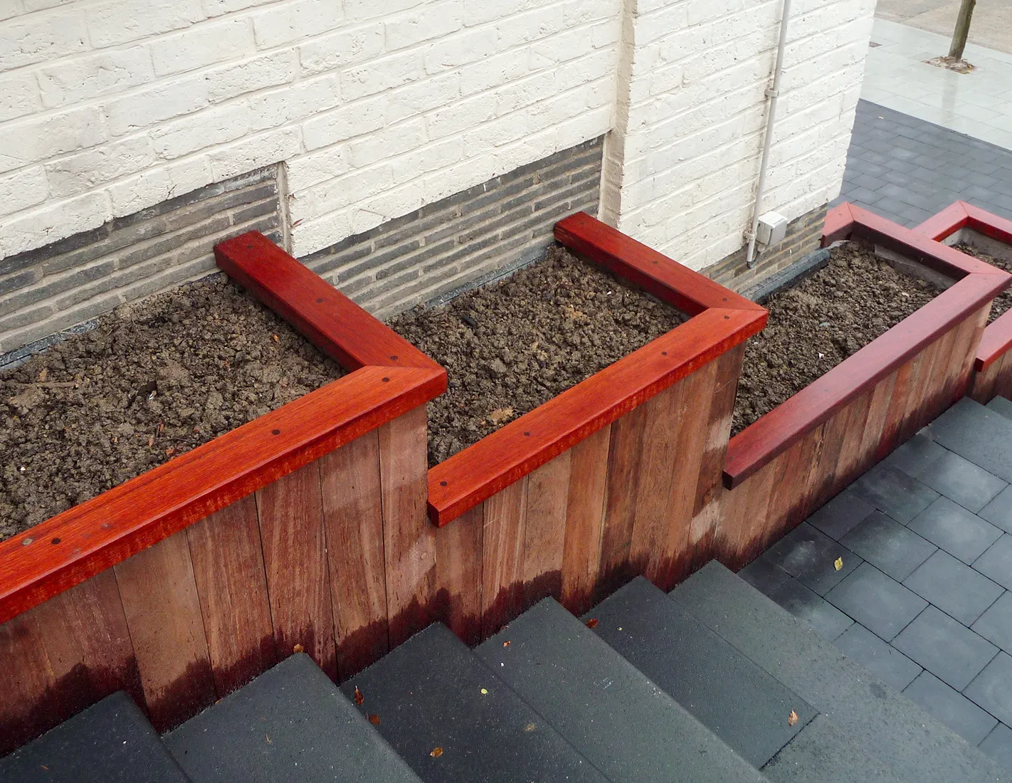 Bacs de plantation en bois exotique bordant un escalier en pierre bleue belge