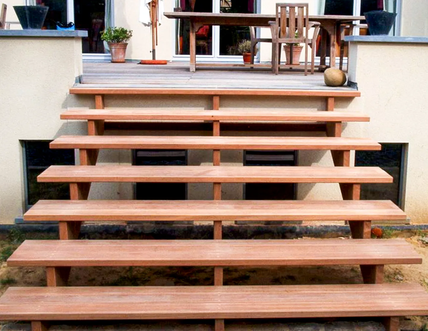 Houten tuintrap in exotisch hardhout met brede treden die toegang geeft tot een houten terras