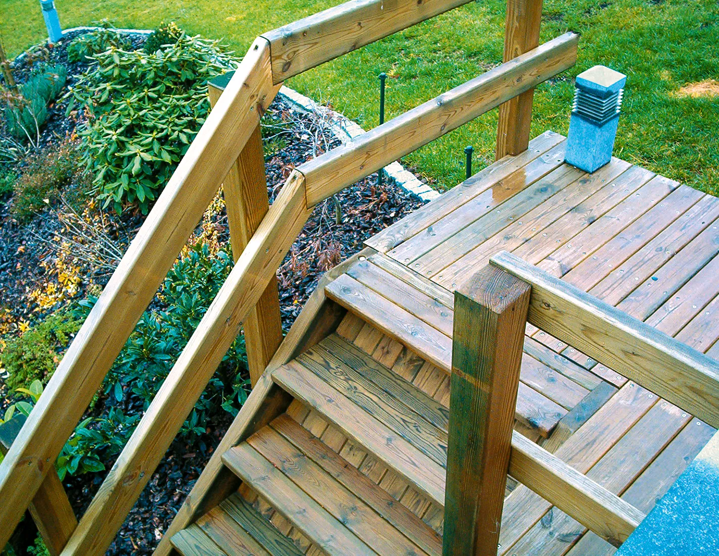 Houten tuintrap in verduurzaamd hout met een leuning met twee regels, die het terras met de tuin verbindt