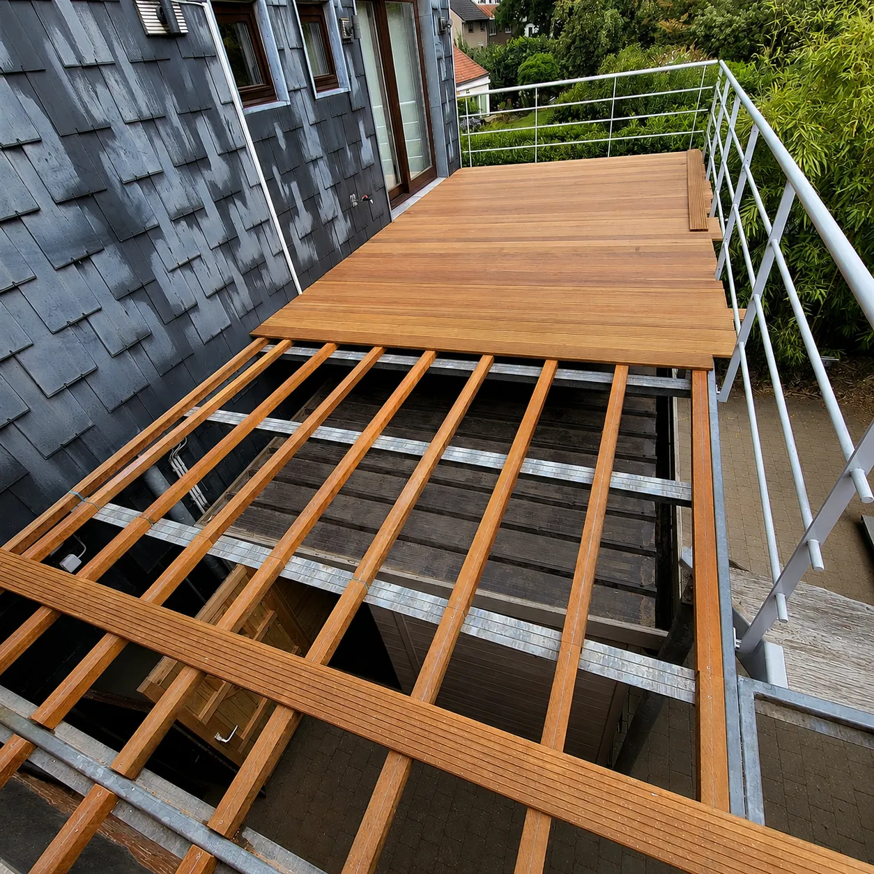 Verhoogde terrasstructuur met hardhouten draagbalken bevestigd op gegalvaniseerde stalen profielen