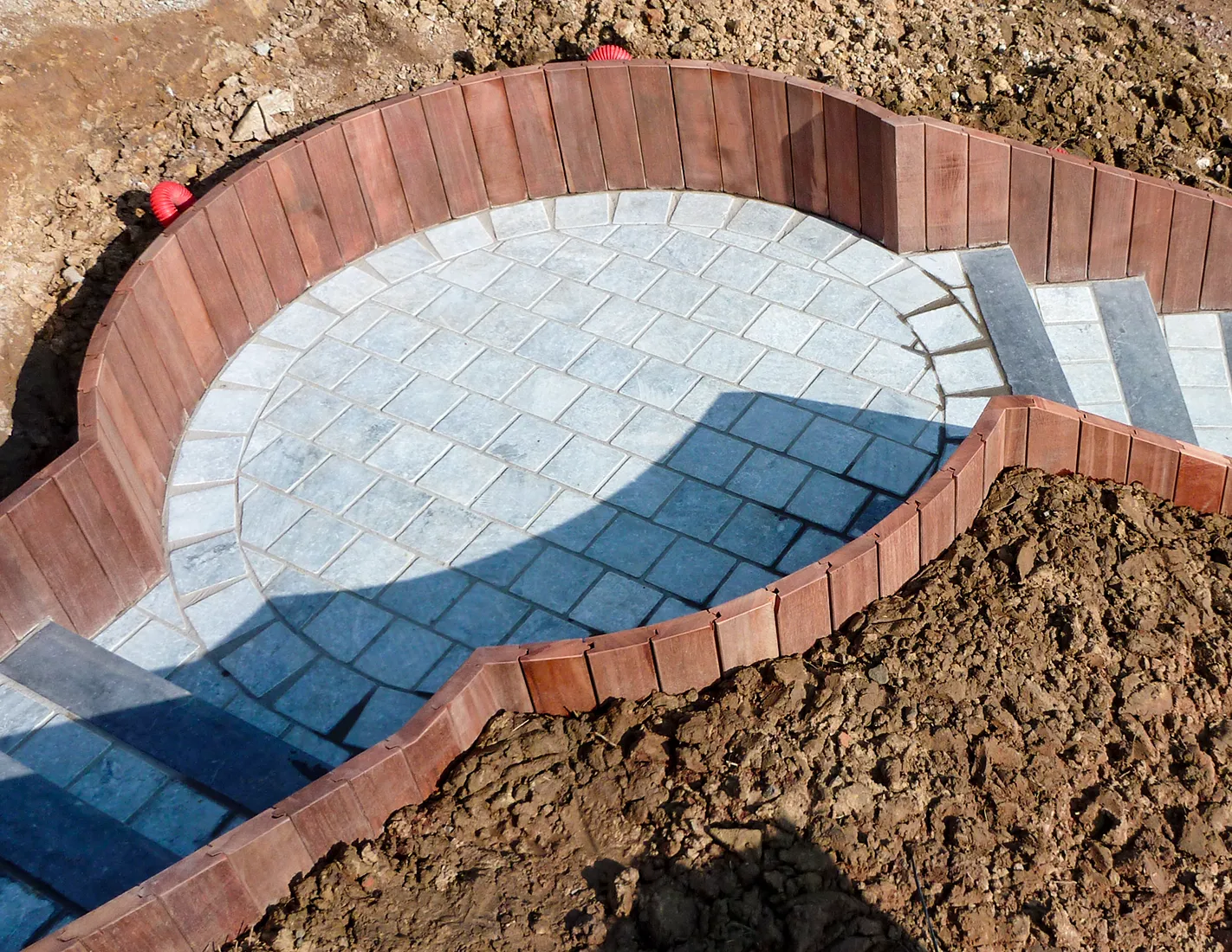Mur de soutènement courbe en palplanches d'azobé rainurées languettées autour d'une terrasse ronde en pierre bleue