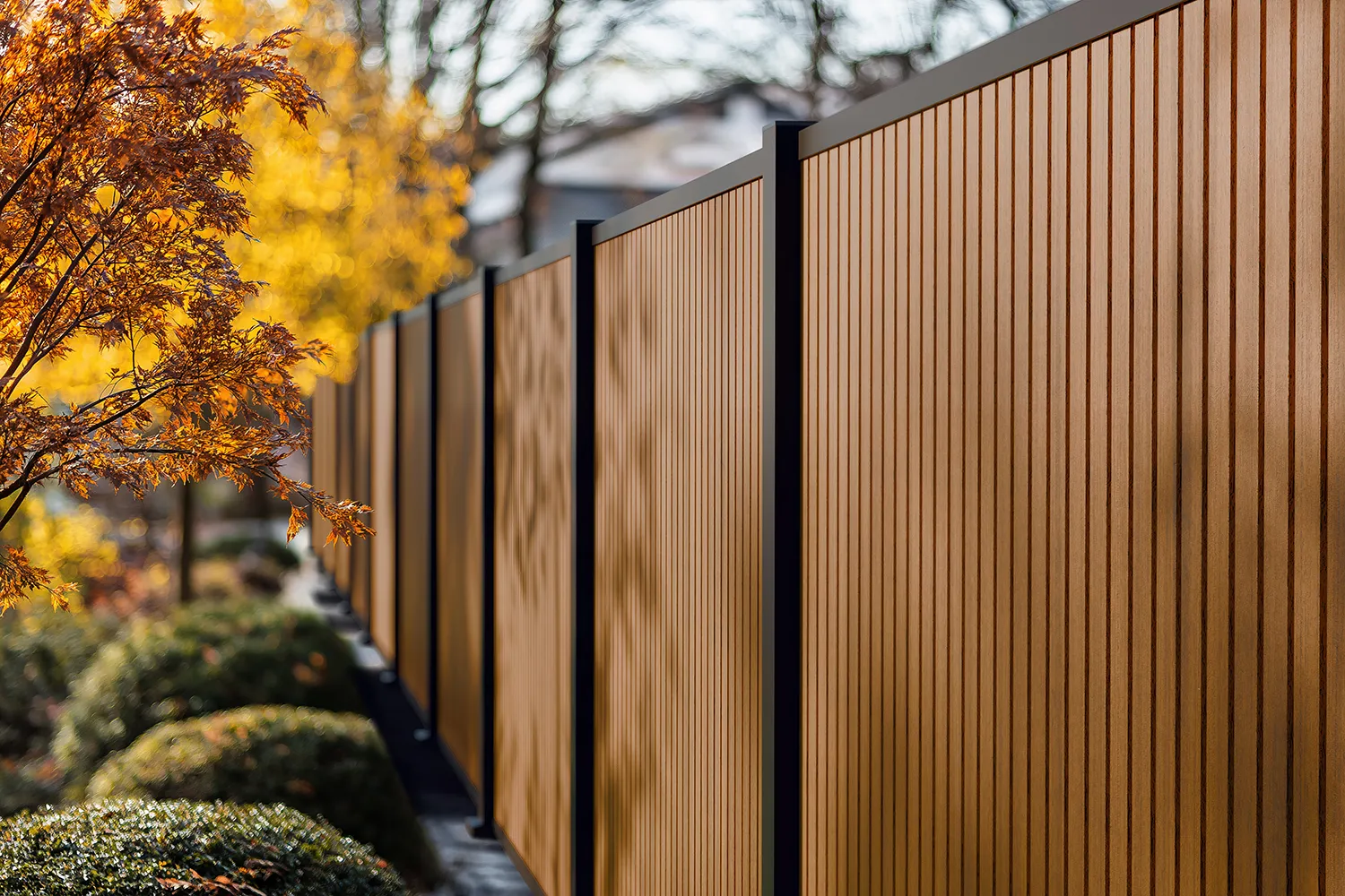 Palissade en planches composite Boston pos&eacute;es &agrave; la verticale, poteaux et profils noirs, le long d&rsquo;un jardin