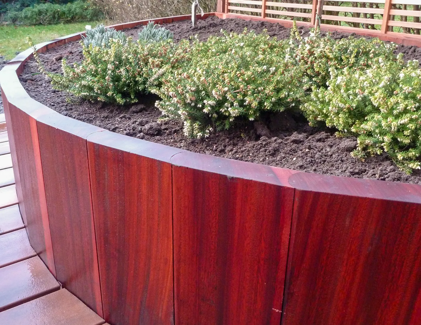 Keermuurtjes in afgeronde damplanken azobé die het talud aan weerszijden van een gekasseide oprit tegenhouden
