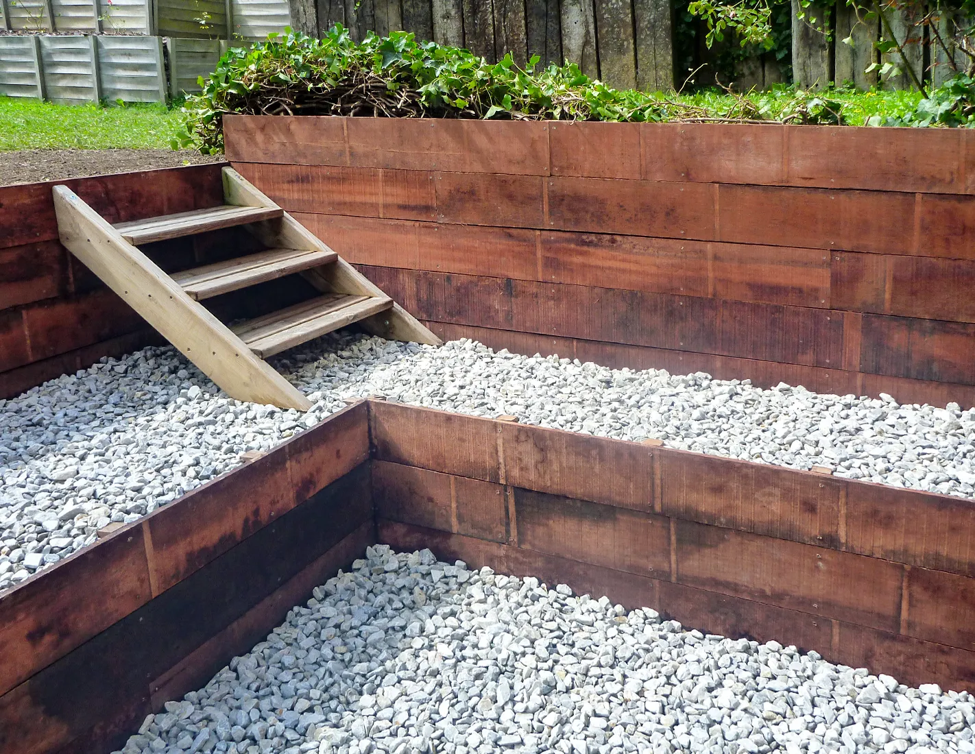 Jardin am&eacute;nag&eacute; en deux niveaux avec murets de retenue de terre en planches d'azob&eacute; et escalier en bois