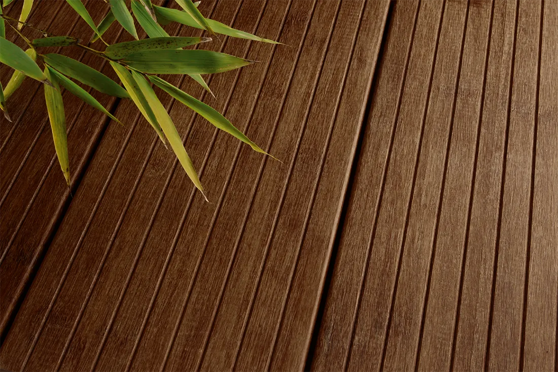 Gros plan sur planche de terrasse en bambou rainur&eacute;e avec feuillage de bambou
