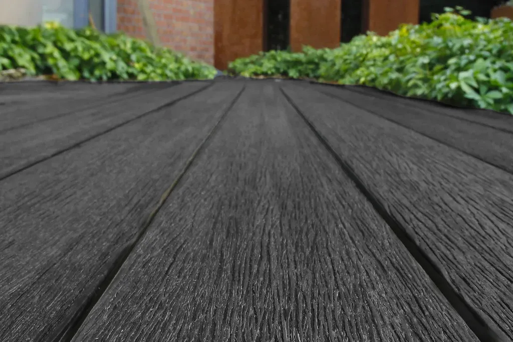 Vue rapproch&eacute;e en contre-plong&eacute;e des lames composite noires avec v&eacute;g&eacute;tation en arri&egrave;re-plan